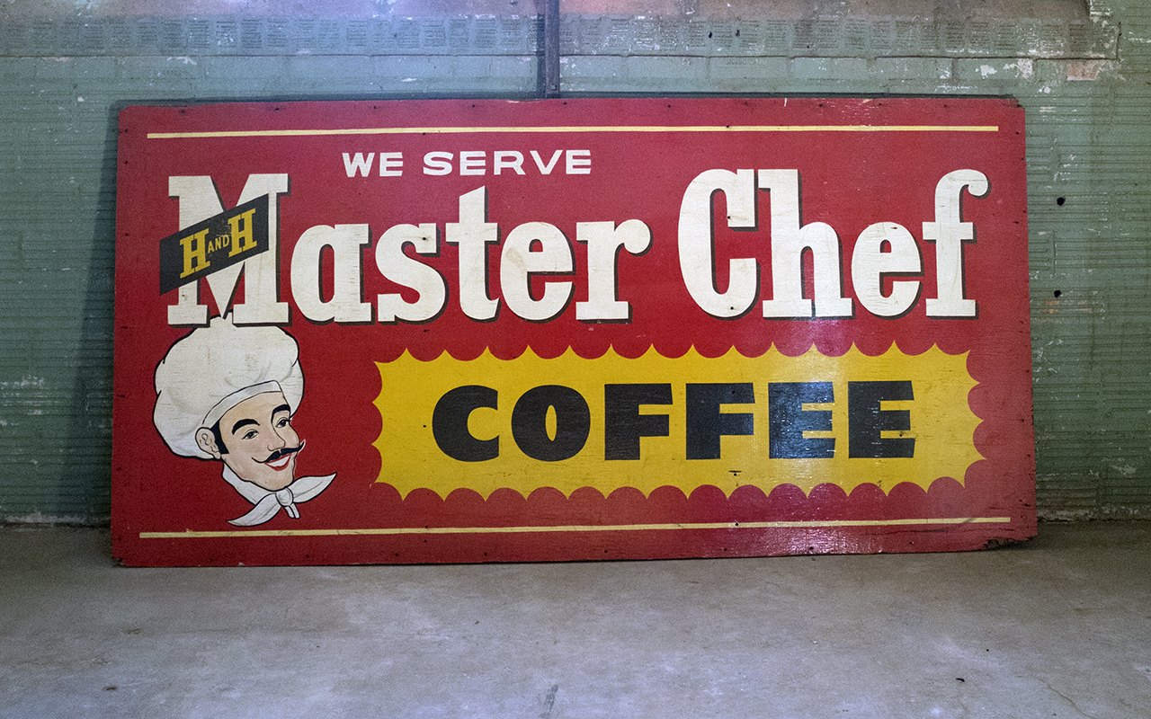 Large red plywood "We Serve" Master Chef Coffee sign, white script Master Chef, H AND H black banner, yellow coffee burst, chef illustration, leaning on brick wall