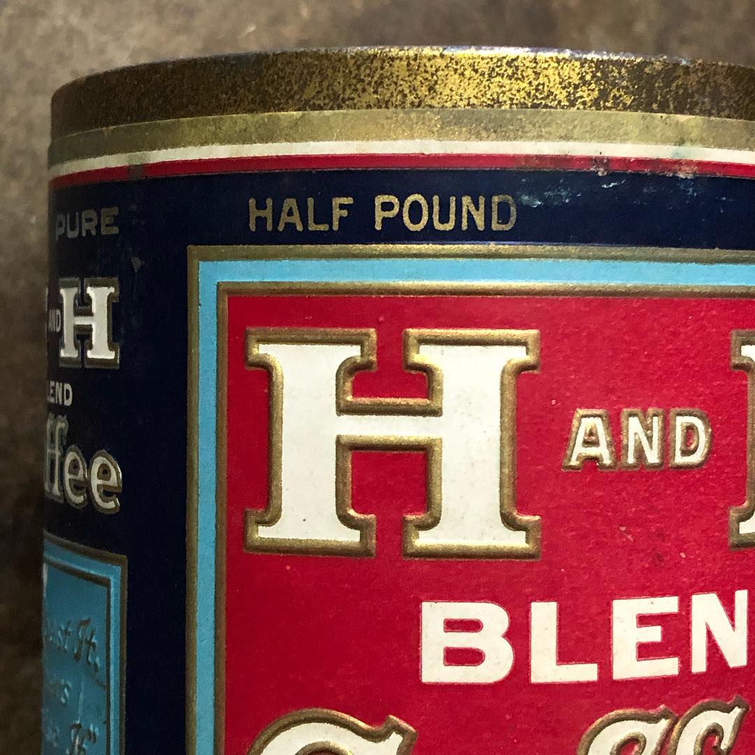 Close-up detail of the embossed gold trim around the "H AND H" lettering at the top of the label, with the "HALF POUND" net-weight line running above and a glimpse of the "We Roast It — Others Praise It" medallion on the left edge.