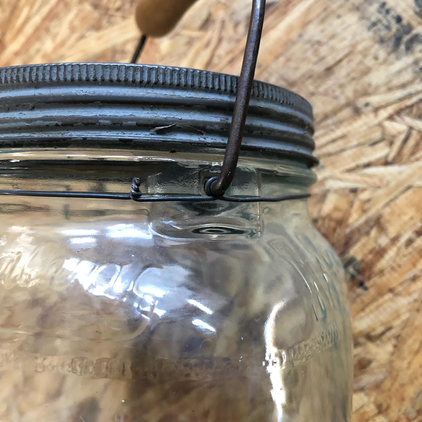Close-up of the wire-bail attachment at the jar's neck, showing the aqua tint in the glass