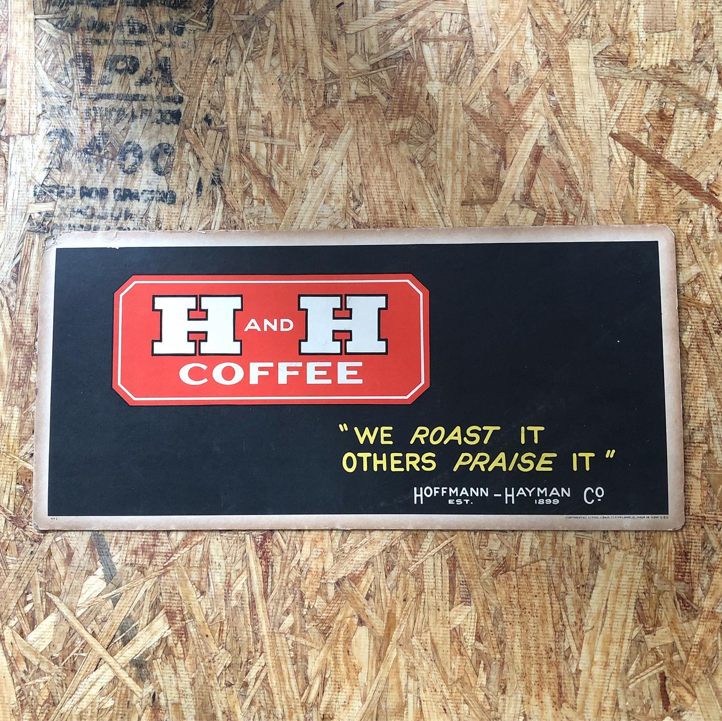 H and H Coffee cardboard sign — black background, red H&H Coffee logo, "We Roast It / Others Praise It" / Hoffmann-Hayman Co Est 1899. Continental Litho. Corp. Cleveland, O. MADE IN U.S.A. C-63, marked No. 1.