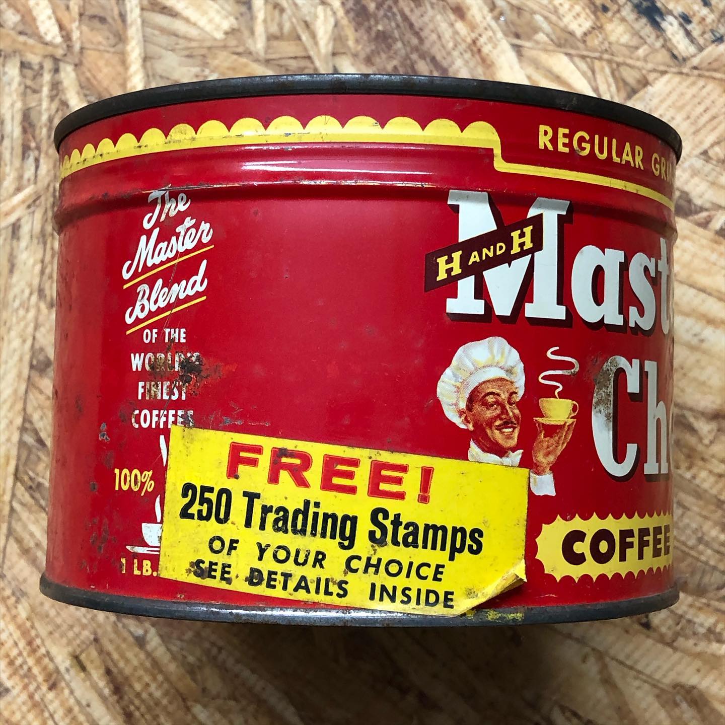 Three-quarter view of the same tin showing the winking Master Chef mascot holding a steaming cup alongside the H AND H Master [Chef] wordmark, "REGULAR GRIND" along the top edge, and the full "FREE! 250 Trading Stamps OF YOUR CHOICE / SEE DETAILS INSIDE" sticker. The left panel is visible with "The Master Blend OF THE WORLD'S FINEST COFFEES" in a sans-serif stack.