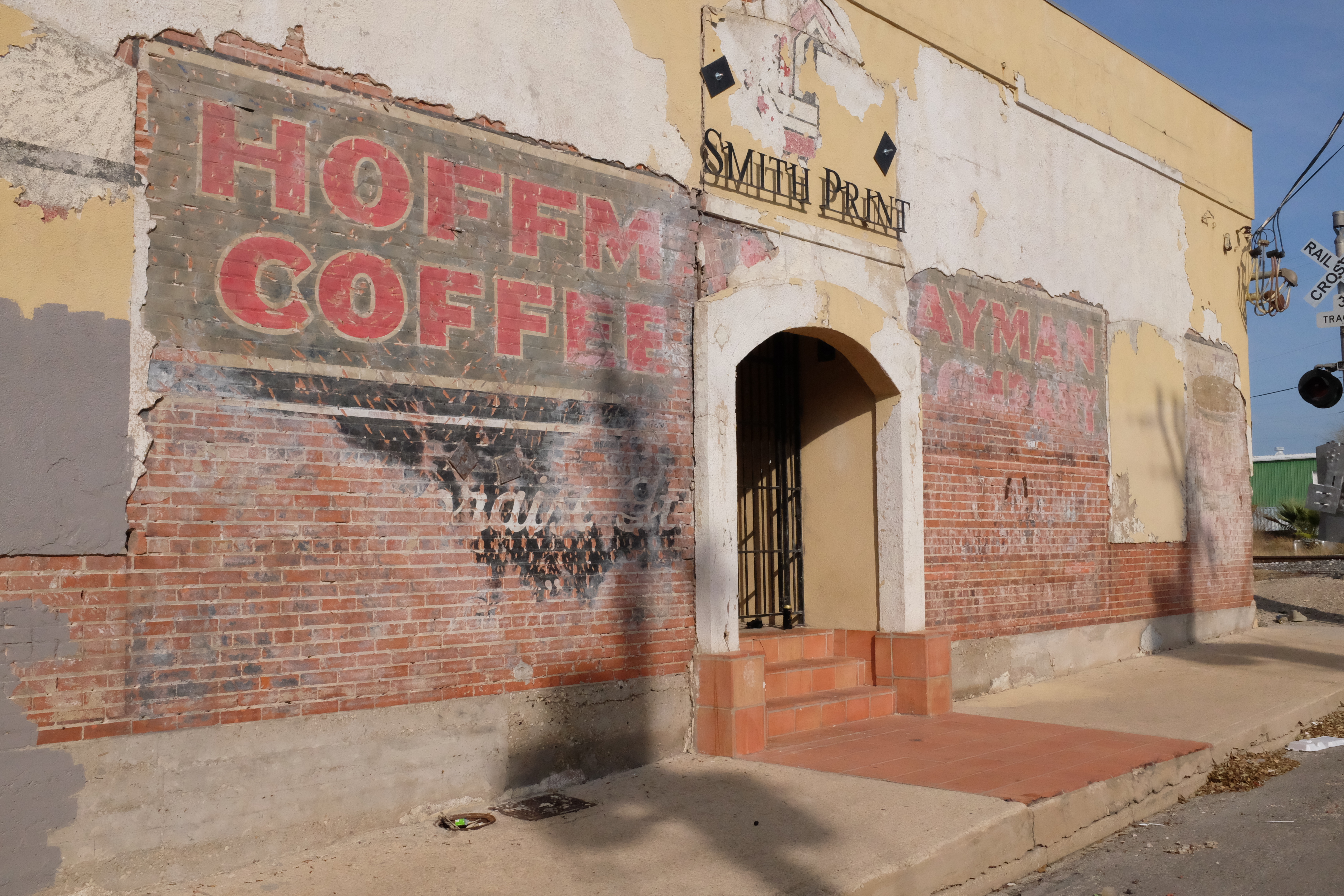 Smith Print entrance — HOFFMAN COFFEE (left of door), HAYMAN COMPANY (right); crossbuck at curb