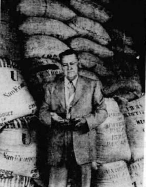 Vertical halftone of an industry executive in a suit standing in front of stacked burlap coffee sacks, The News, 23 Jul 1943