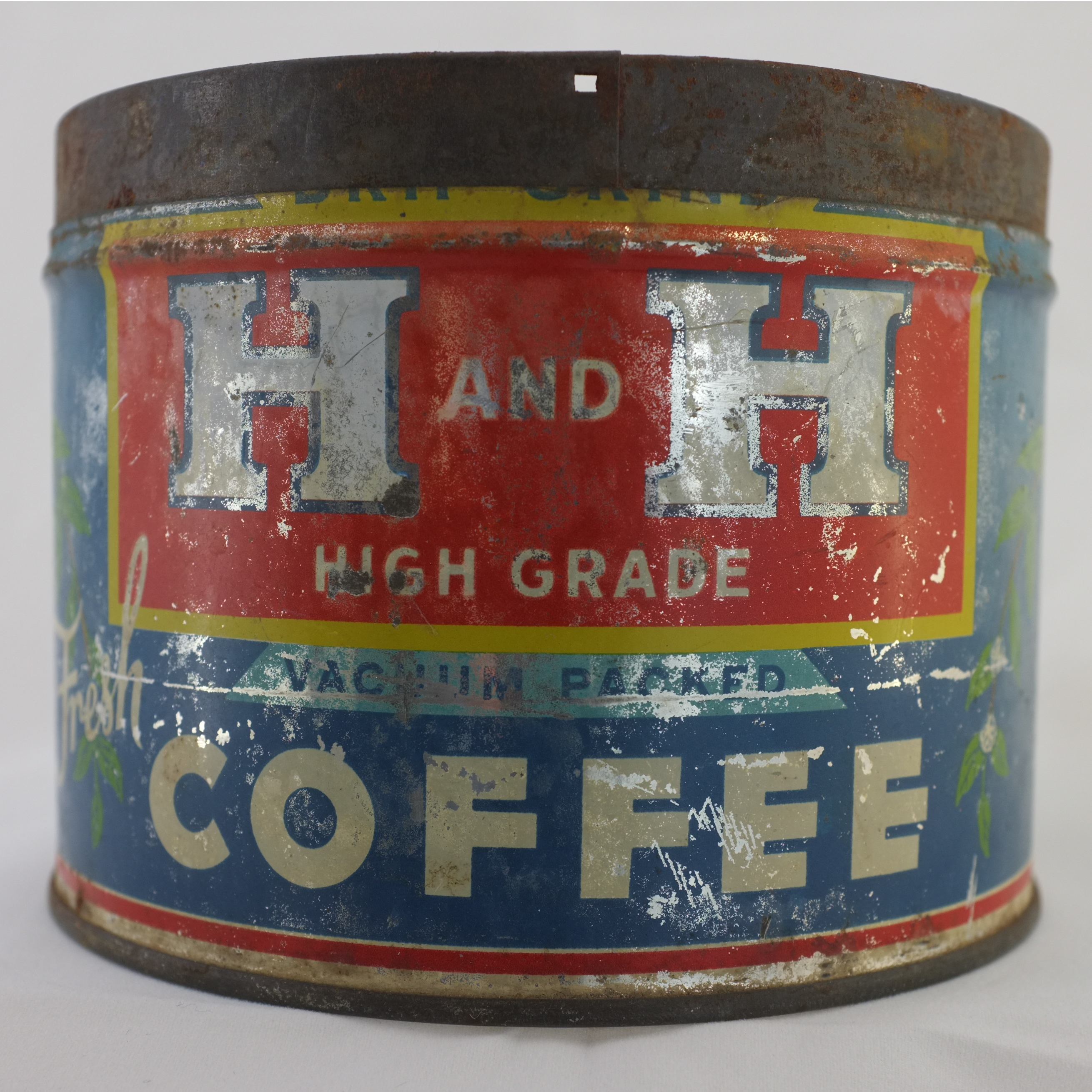 Cylindrical H and H High Grade vacuum-packed coffee tin, red and navy with VACUUM PACKED, Drip Grind, weathered and rusted top, heavy paint loss