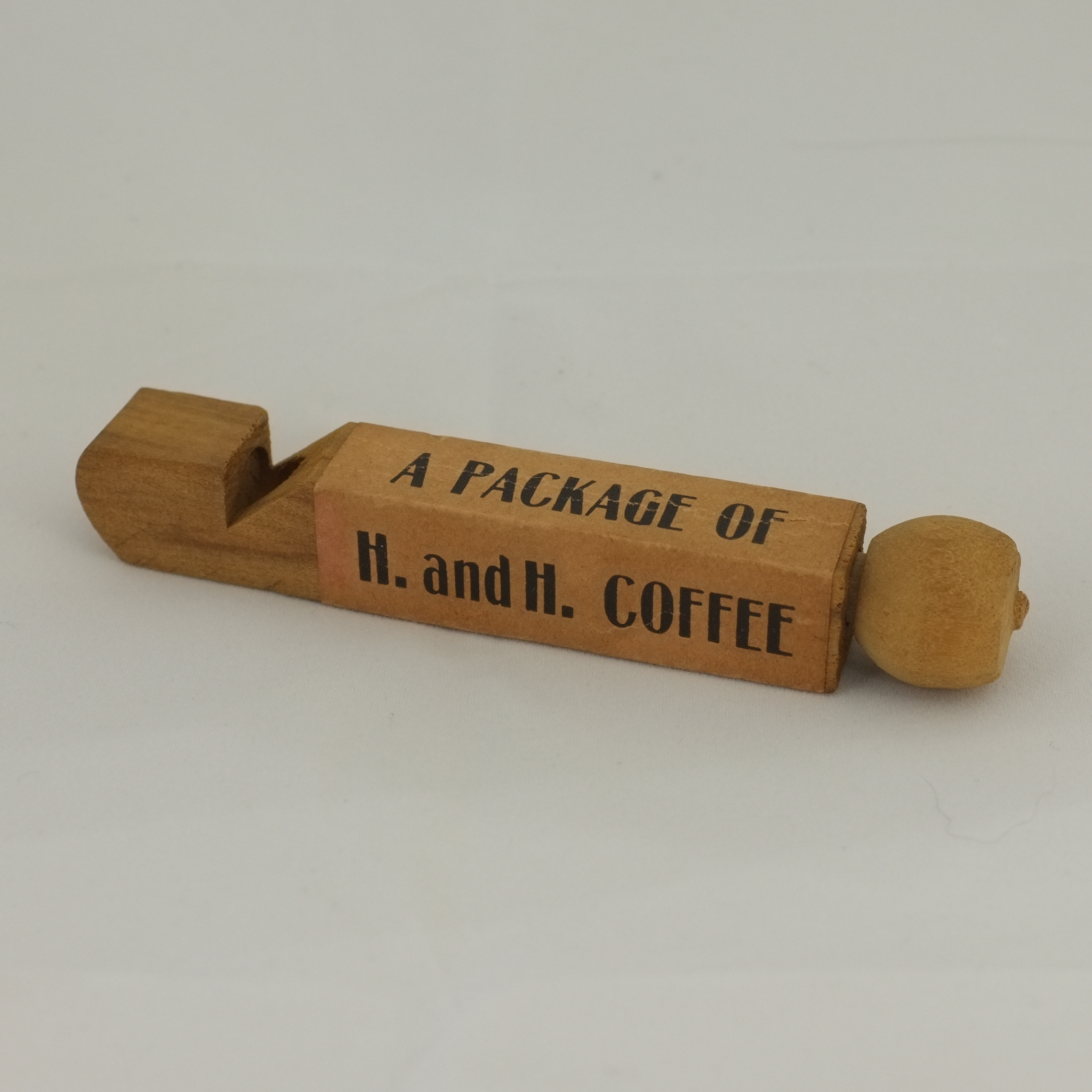 H. and H. coffee quail- or call-type wooden slide whistle, kraft ad band, light wood Wooden quail- or call-type H. and H. coffee premium whistle, kraft A package of / H. and H. coffee ad band