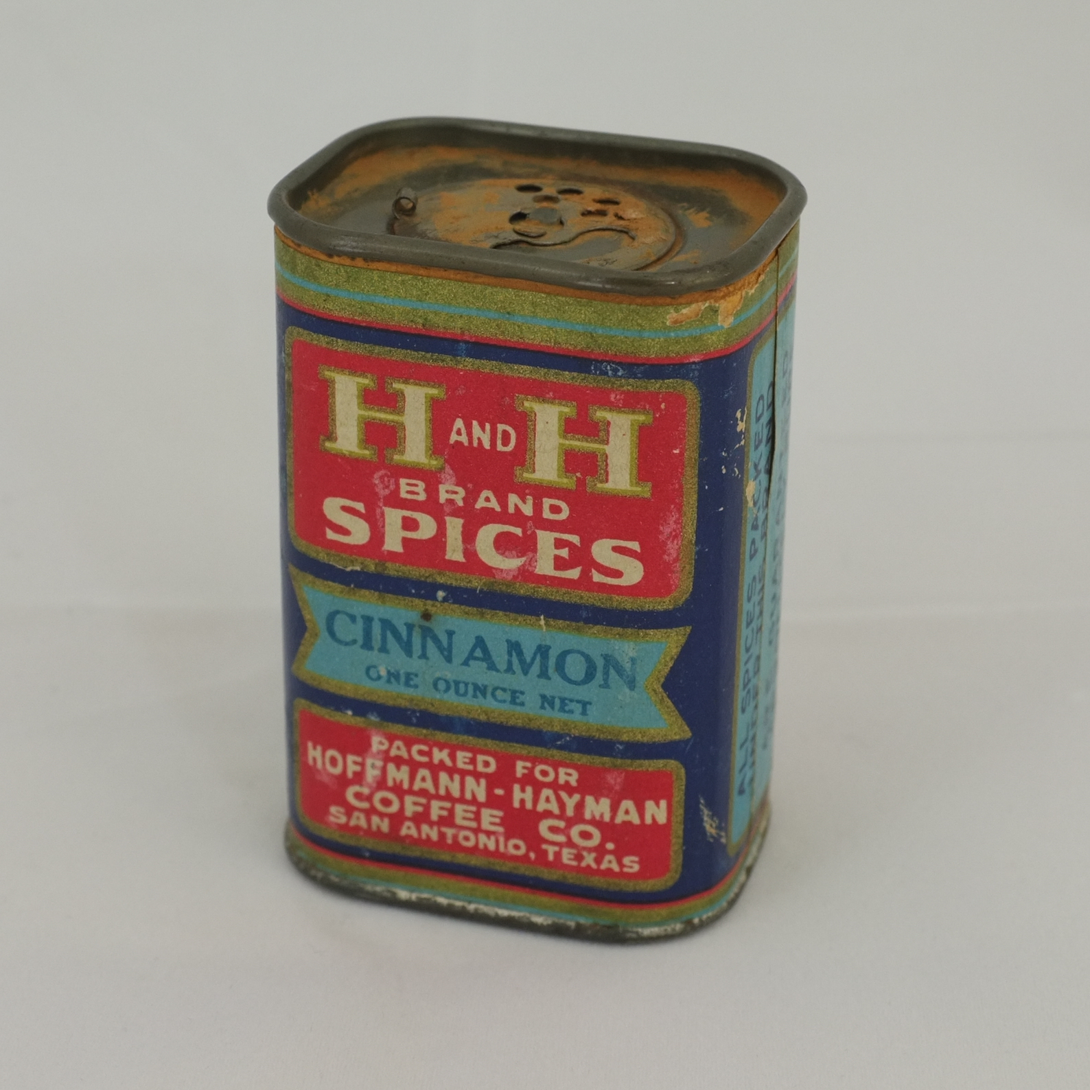 Rectangular H and H Brand Spices one-ounce cinnamon tin: red, gold, and blue label, CINNAMON / ONE OUNCE NET, packed for Hoffmann-Hayman Coffee Co., San Antonio, Texas, with rotating shaker top