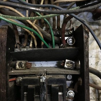 **8 March 2016** (**Apple iPhone 6s**) — open **industrial panel** interior: **terminal strips**, **green** equipment-ground conductors, **black/red/tan** branch wiring, tops of **snap** breakers — dusty **first-generation thermoplastic** install at Hoffmann-Hayman.