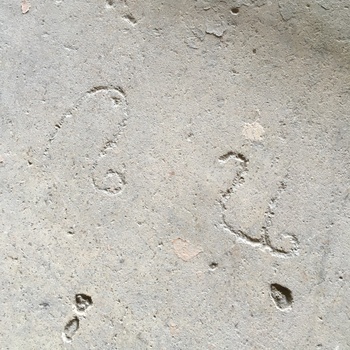 **12 June 2016** (**Apple iPhone 6s**) — top-down on **grey pitted concrete** at Hoffmann-Hayman: shallow **etched or scribed** figures reading loosely as **22** or similar pair of numerals — **floor or deck marking** in the shell.