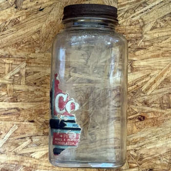 H and H Blend Coffee one-pound smooth-body Crystalvac jar with brown oxidized screw lid and near-total paper label loss, surviving left-face strip showing the PERC-O-DRIP GRIND panel and a partial HOFFMANN imprint, photographed 2026-07-21
